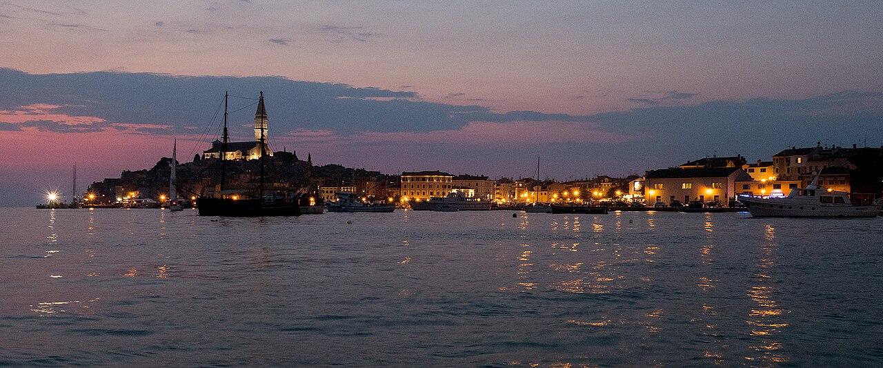 Rovinj's waterfront and bell tower glowing across the water at dusk